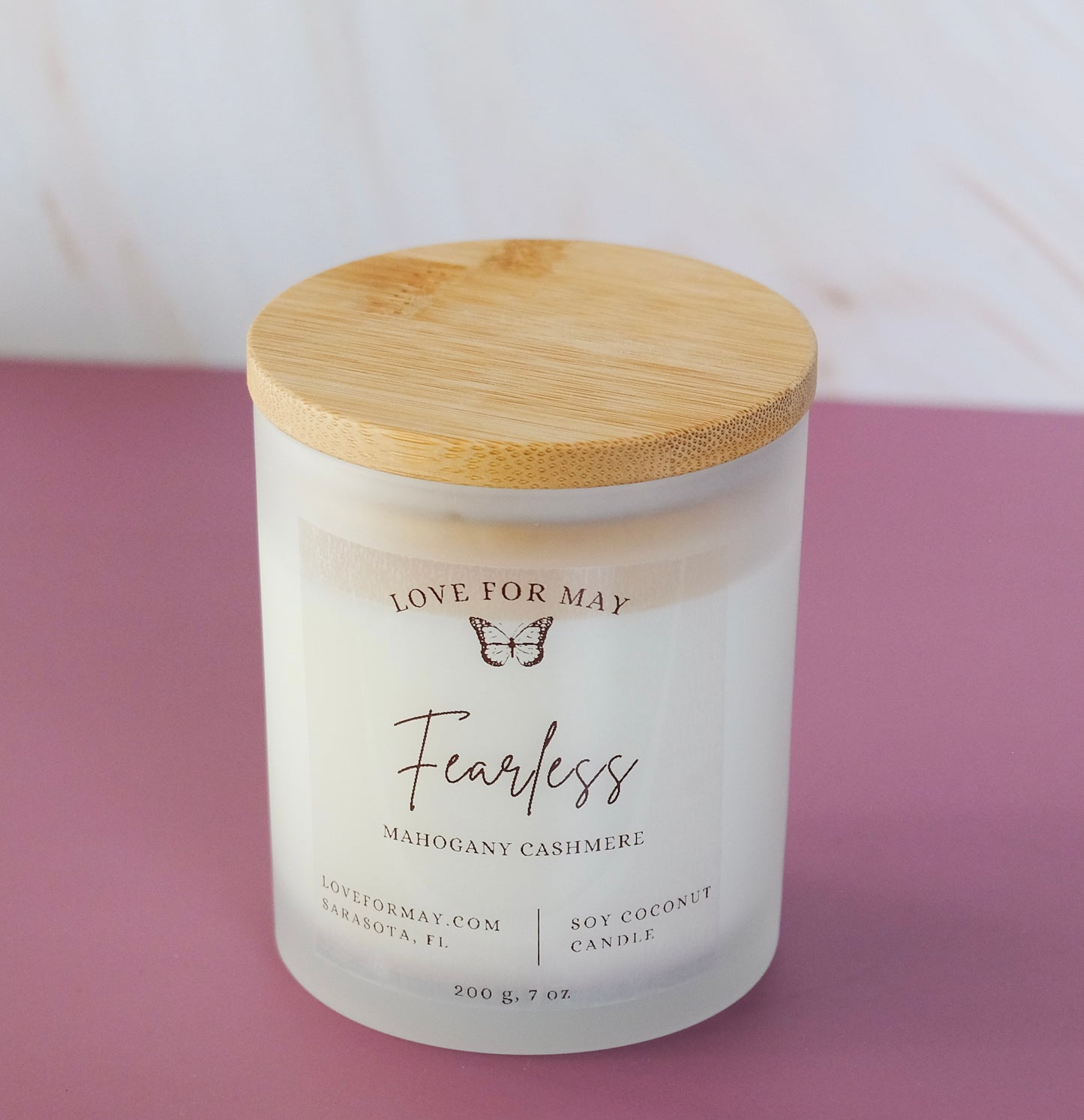 Mahogany cashmere scented candle in a frosted glass jar with a bamboo lid and the word fearless on the label.