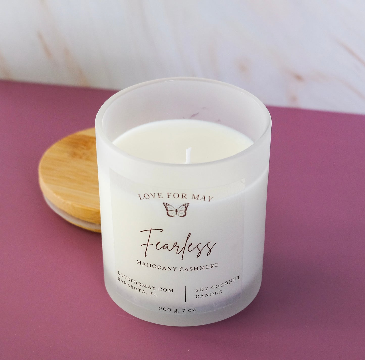 Mahogany cashmere scented candle in a frosted glass jar with the word fearless on the label.