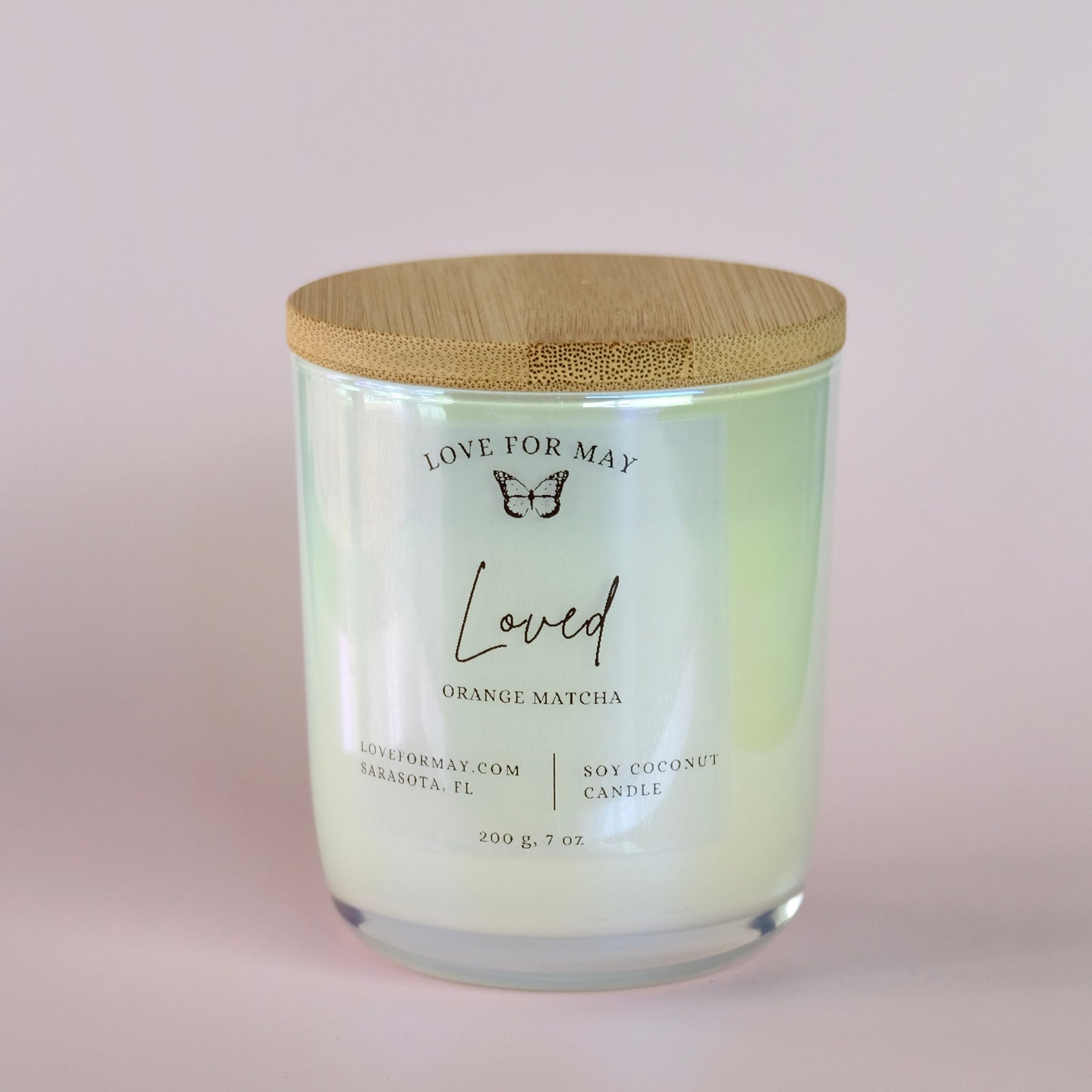 Orange Matcha scented candle in a white iridescent glass jar with a bamboo lid and the word loved on the label.