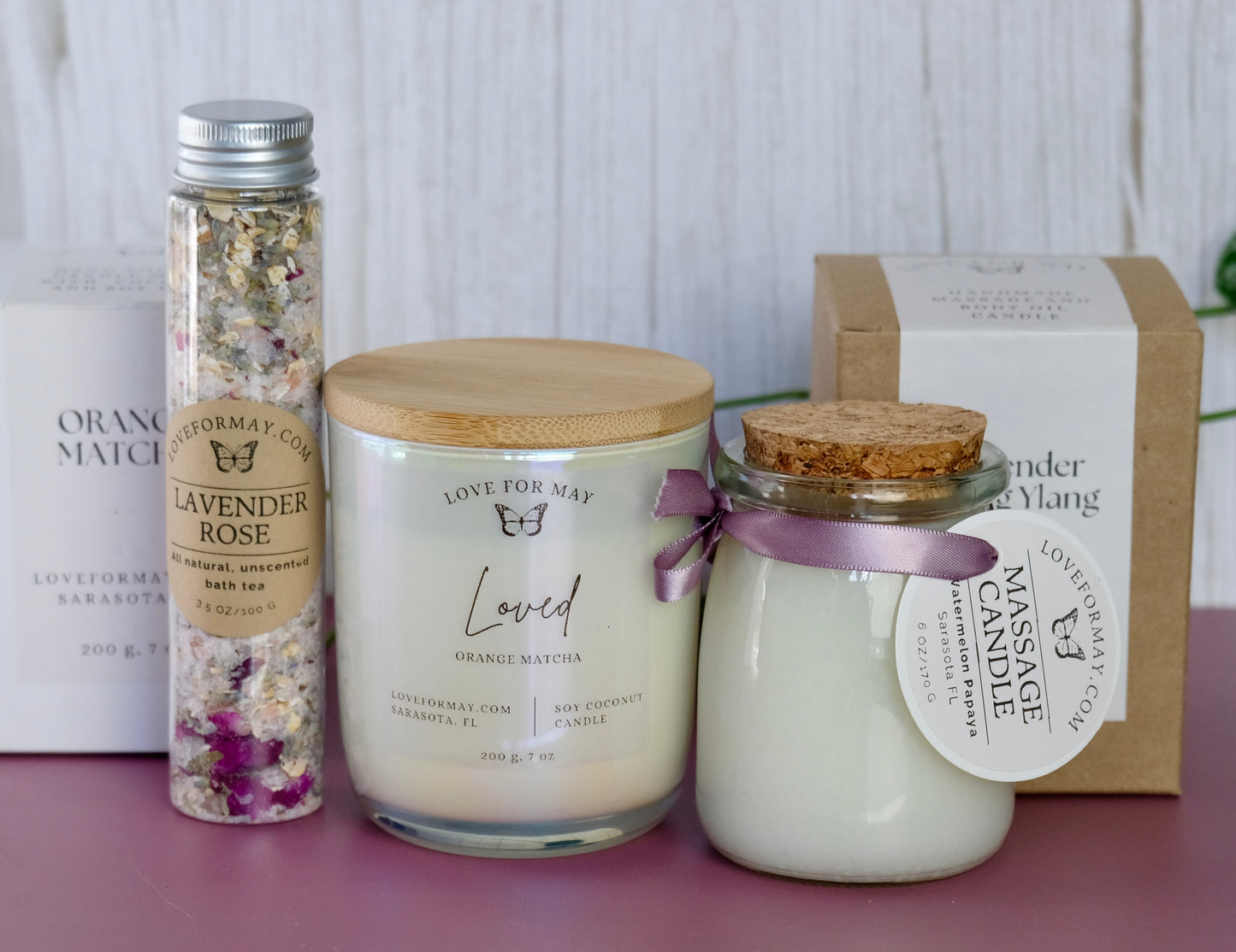 A tube of rose lavender bath tea and bath salts, an iridescent manifestation candle, and a body oil candle