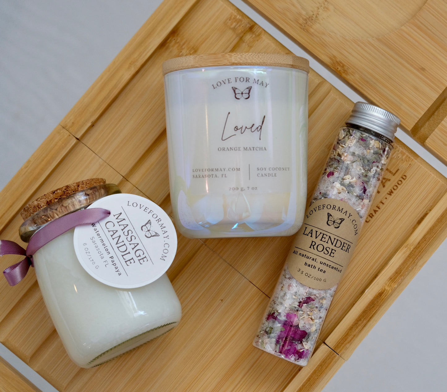 A tube of rose lavender bath tea and bath salts, an iridescent manifestation candle, and a body oil candle