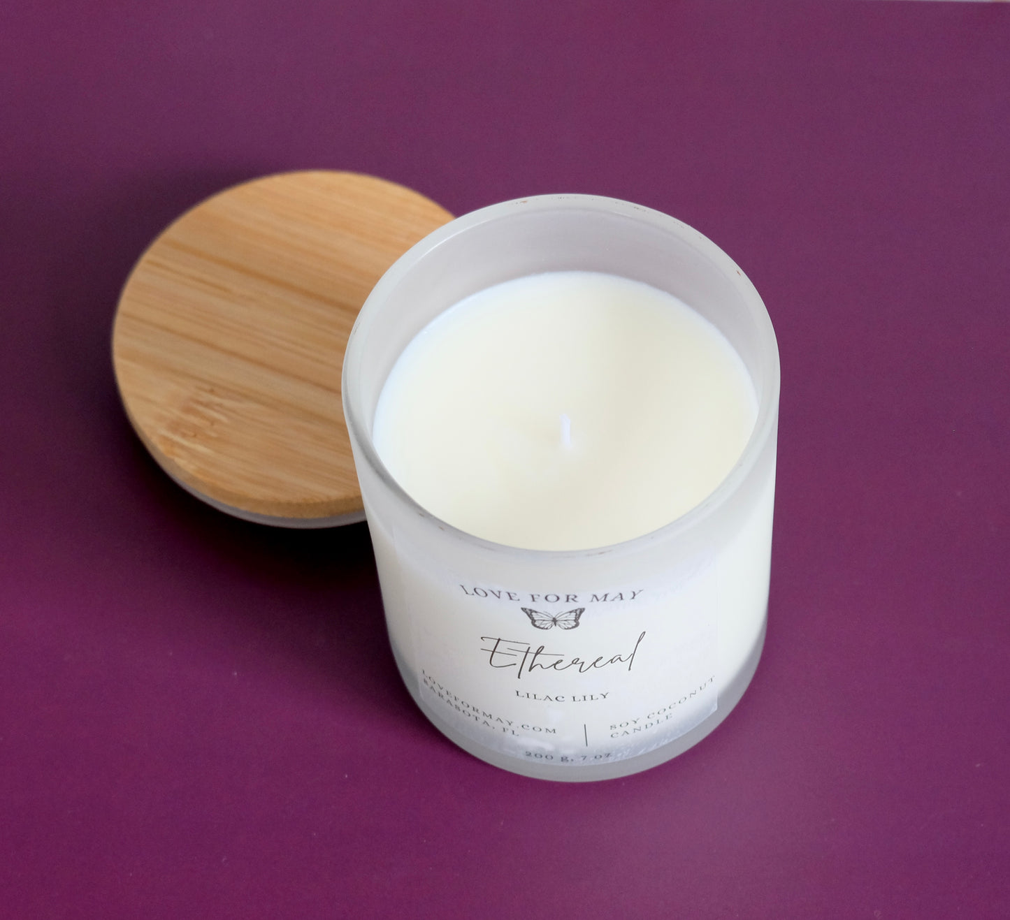 Handmade manifestation candle with a wooden lid and the word ethereal on the label