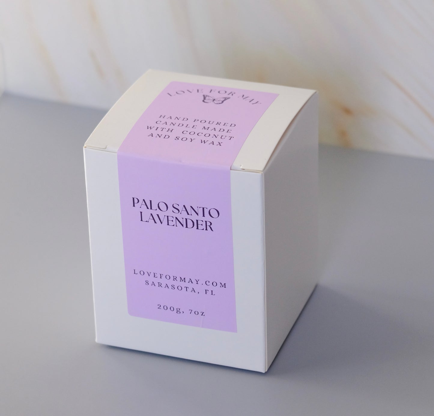 A white candle box with a purple label