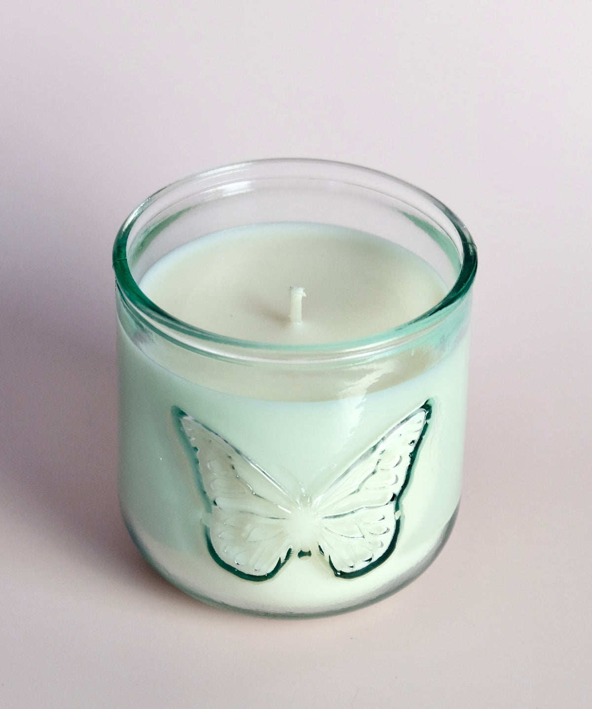 Candle in a glass jar with a butterfly design on a light background