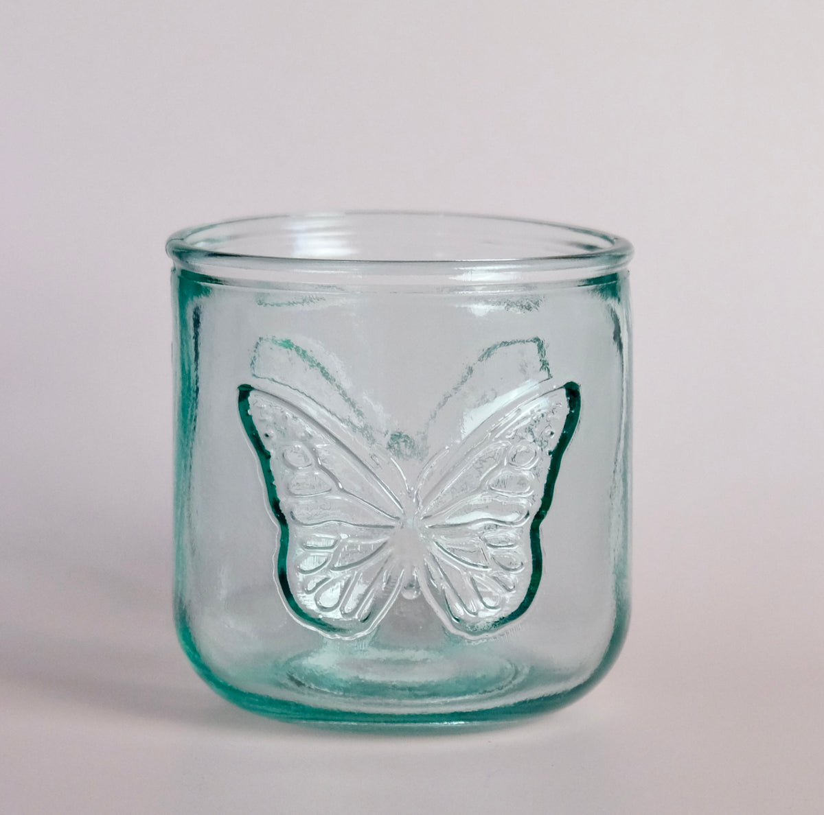 Clear glass jar with a butterfly design on a light pink background