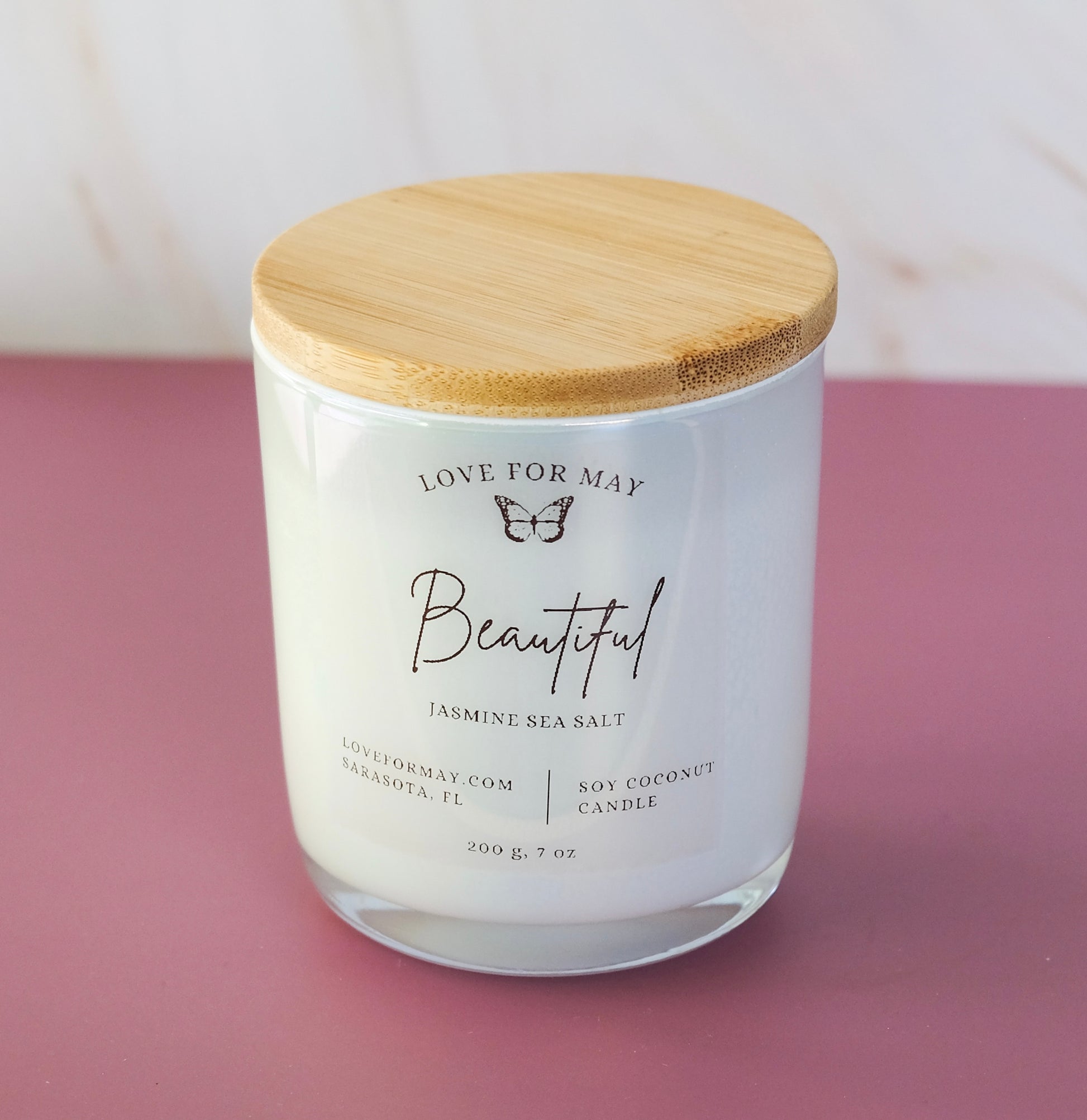 Jasmine Sea Salt scented candle in a frosted glass jar with a bamboo lid and the word beautiful on the label.