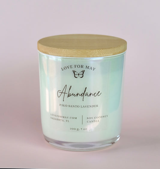 Palo Santo Lavender scented candle in a white iridescent glass jar with a bamboo lid and the word abundance on the label.