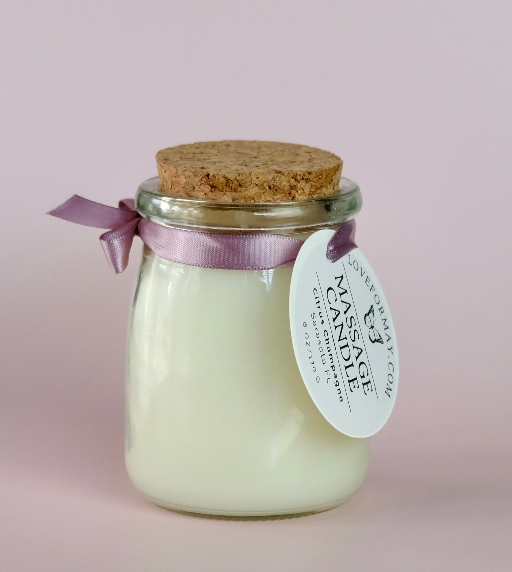 A handmade citrus body oil candle in a glass jar with a cork lid