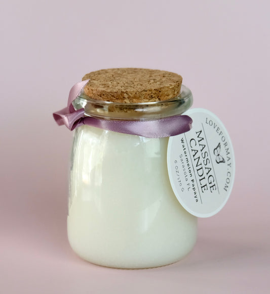 A handmade watermelon scented massage candle in a glass jar with a cork lid