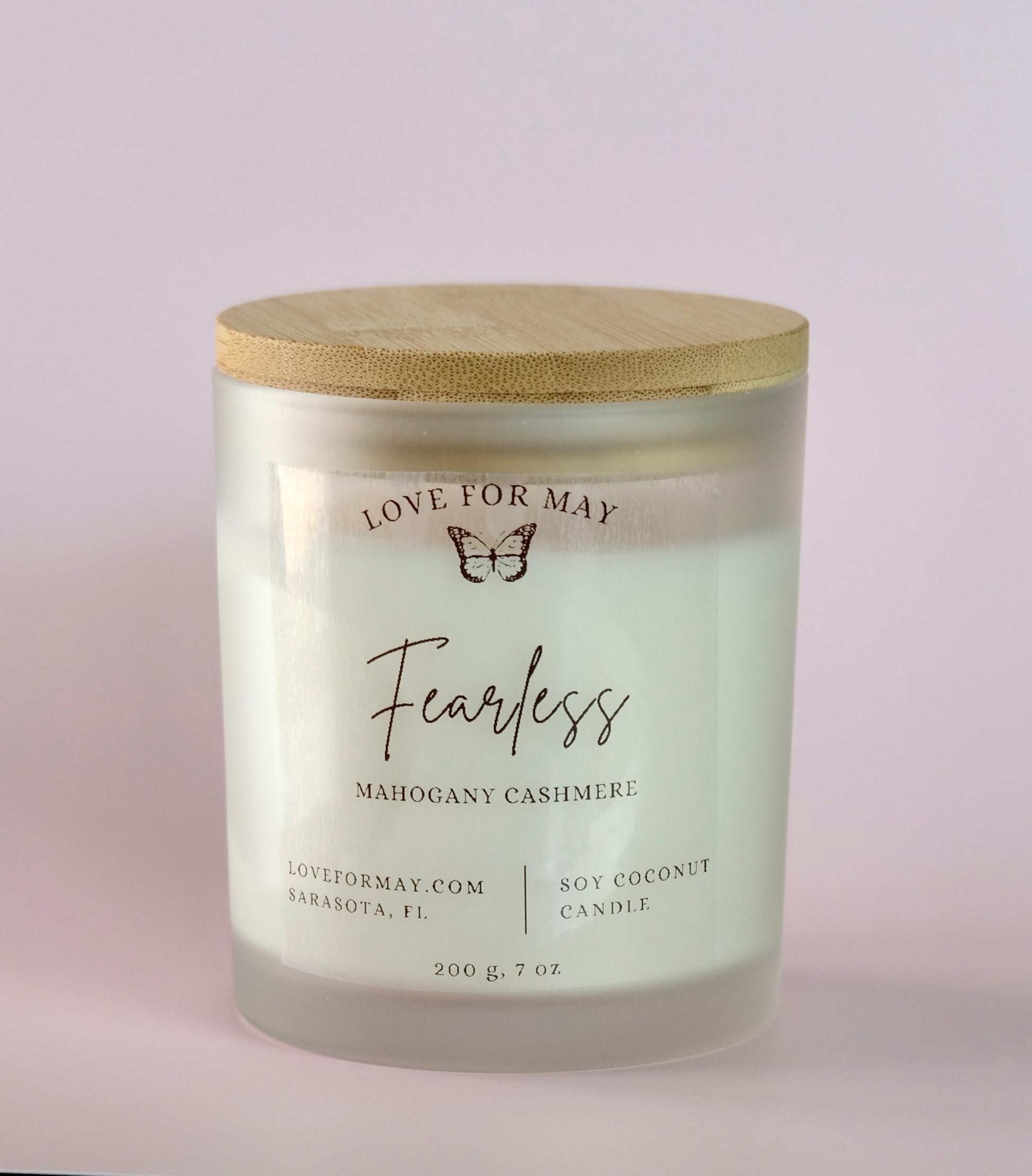 Mahogany cashmere scented candle in a frosted glass jar with a bamboo lid and the word fearless on the label.