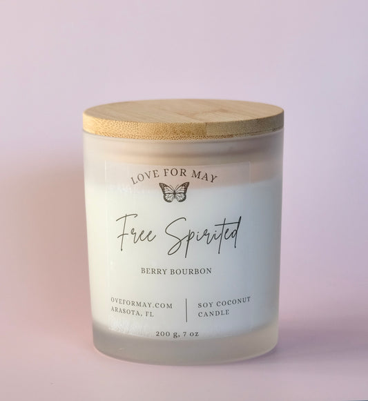 Frosted glass container candle with a bamboo lid, the words Free Spirited on the label and scented Berry Bourbon.