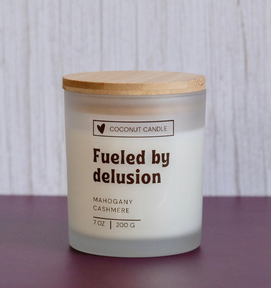 Fun affirmation candle with the words Fueled by Delusion 