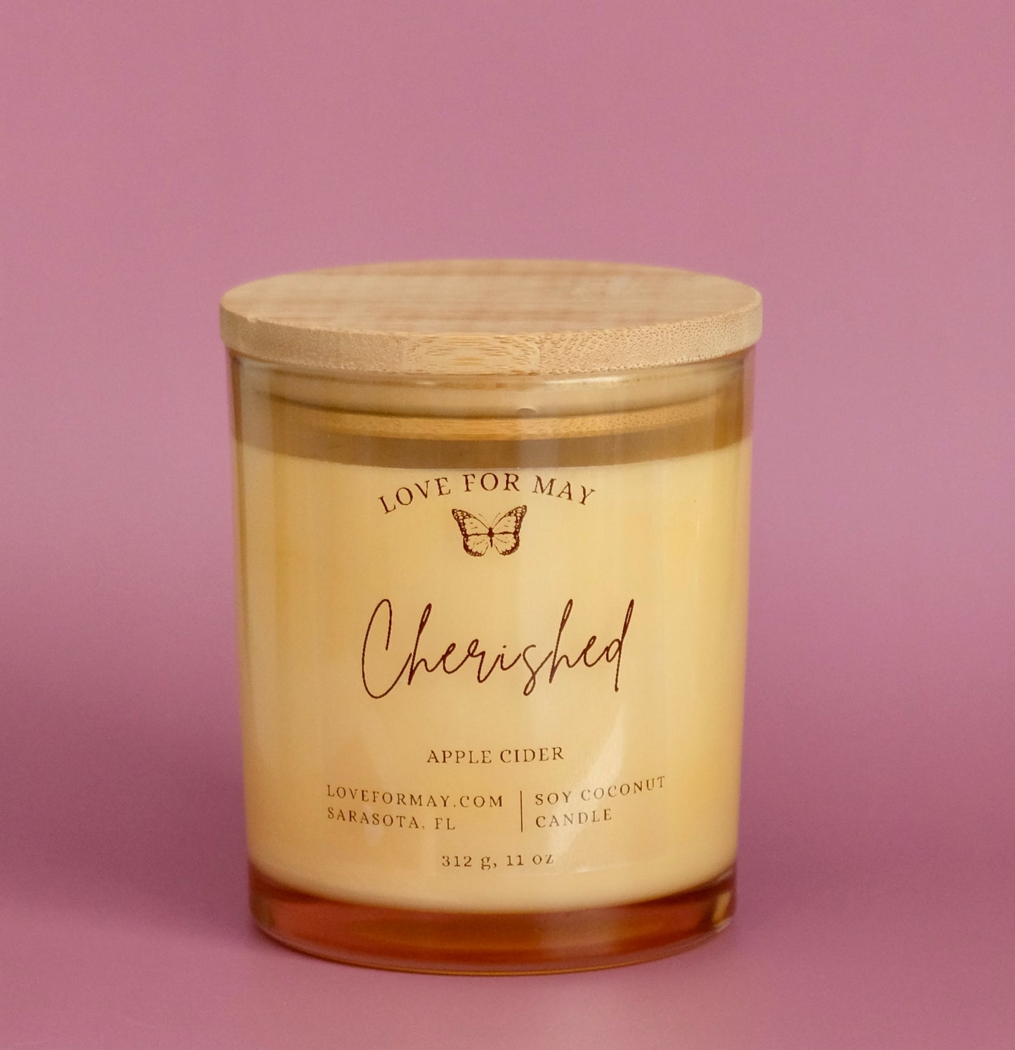 A light amber glass container candle with a wooden lid and the affirmation Cherished.