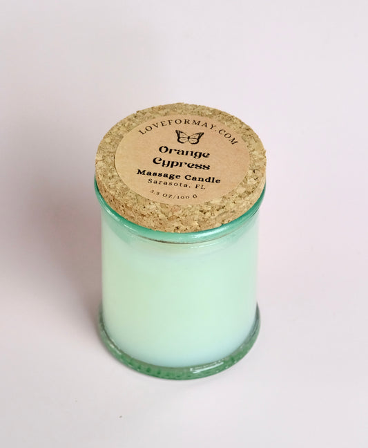 Massage candle in a clear glass jar with a green tint and a cork lid.