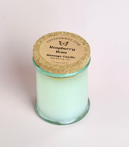 Massage candle in a clear glass jar with a green tint and a cork lid.