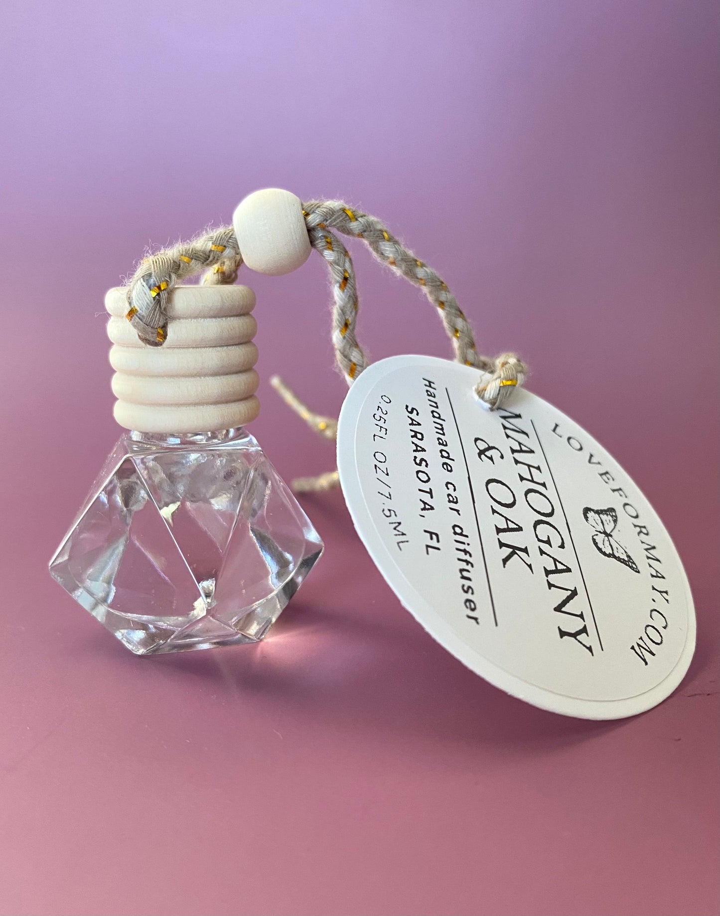 Mahogany & Oak scented car diffuser in a diamond shape glass bottle with a wood lid and a string.