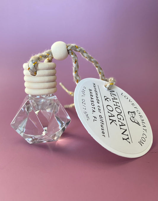 Mahogany & Oak scented car diffuser in a diamond shape glass bottle with a wood lid and a string.