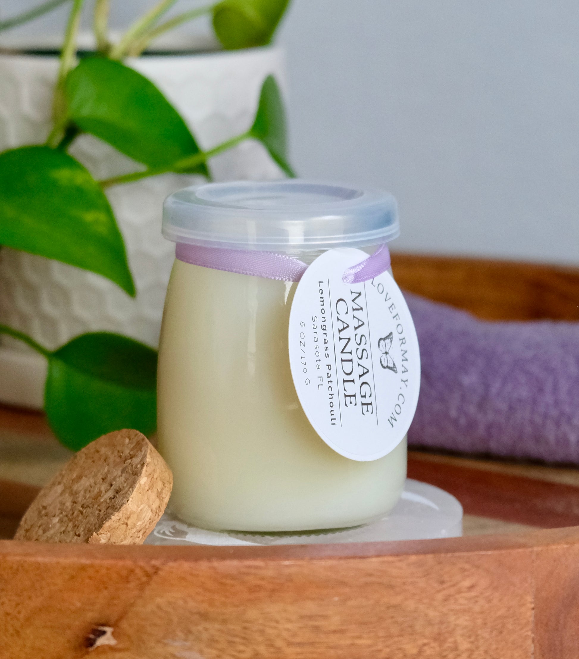 Clear massage candle jar with a plastic lid on top and a cork lid on the side