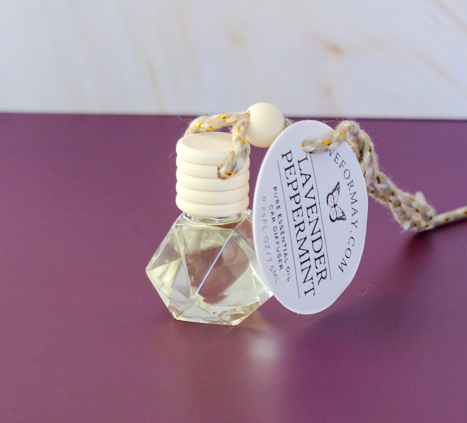 Lavender Peppermint essential oil car diffuser in a diamond shape glass bottle with a wood lid and a string.