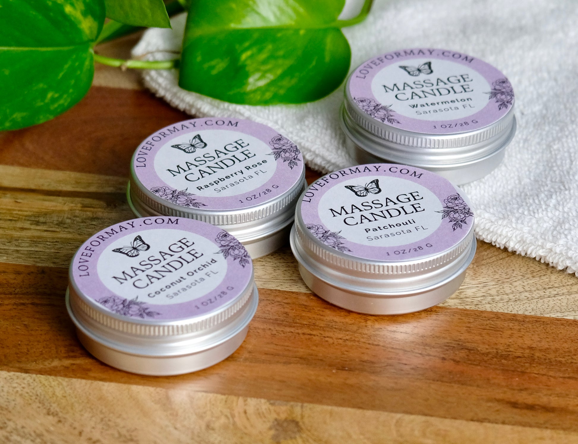 Massage candles with purple labels on a wooden surface