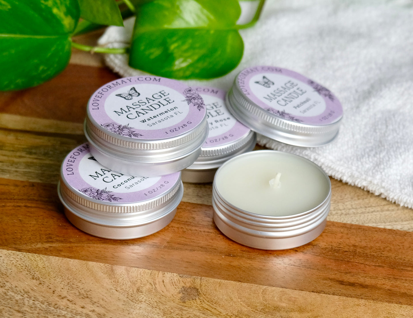 Massage candles with purple labels on a wooden surface