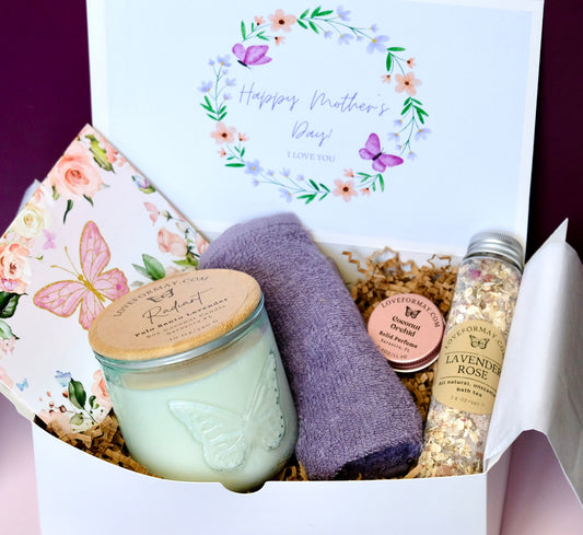 Gift box with a candle, towel, solid perfume and bath salts on a floral and butterfly-themed card.