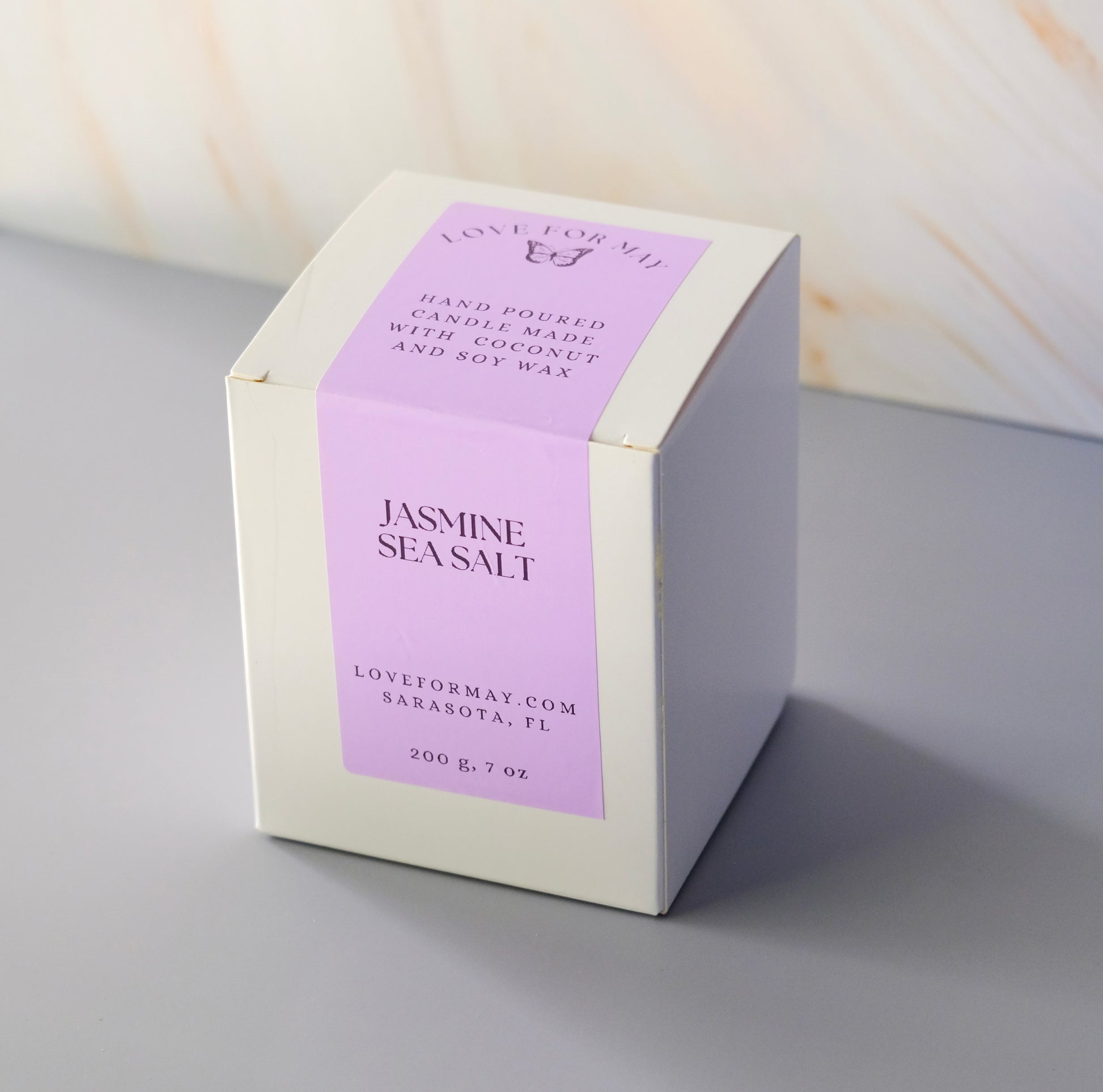 A white candle box with a purple label