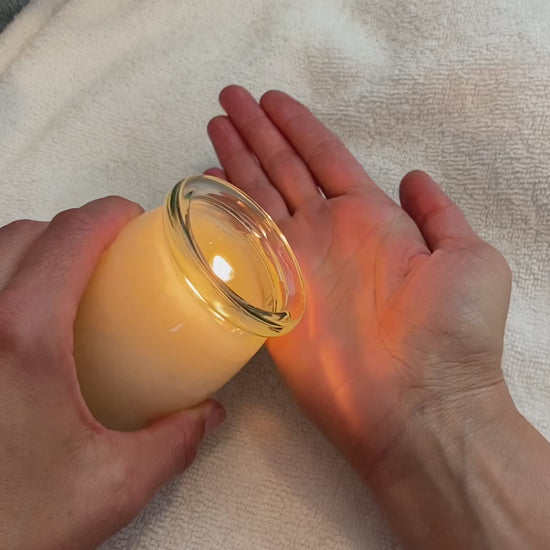 Pouring oil from a massage candle into hands and massaging hands and arm.